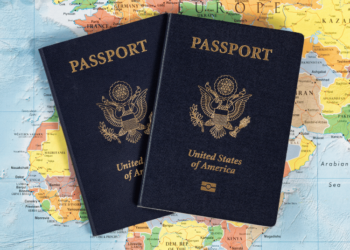 Pair of passports laying on a map of the world.