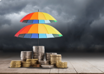 Stormy background with umbrellas over stacks of coins signifying wealth protection.