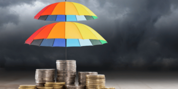 Stormy background with umbrellas over stacks of coins signifying wealth protection.