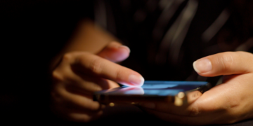 Doom-scrolling on a cell phone in the dark.