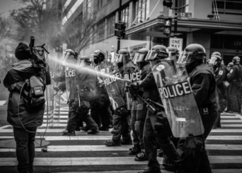 Riot police dispersing a water cannon on protestors.