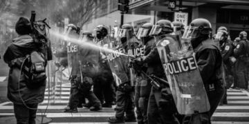 Riot police dispersing a water cannon on protestors.