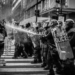 Riot police dispersing a water cannon on protestors.