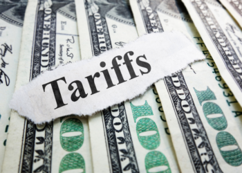 $100 bills laid out with the word "Tariffs" written over them.