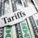 $100 bills laid out with the word "Tariffs" written over them.